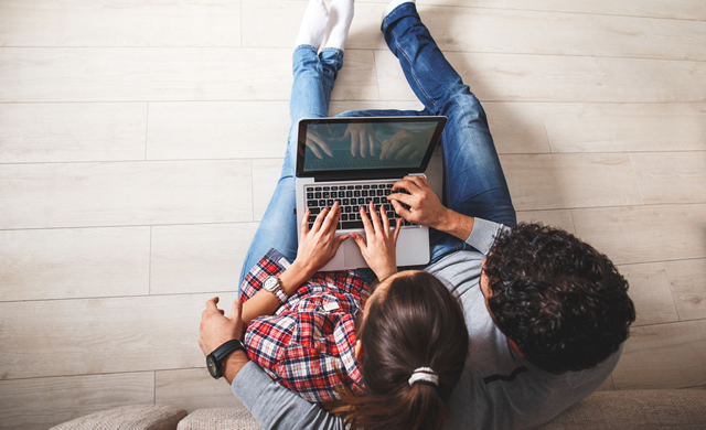 Overhead view of couple using computer on couch