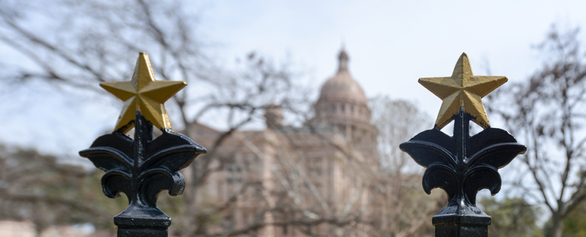 Texas Capitol in background with brass stars from the Capitol fence in foreground